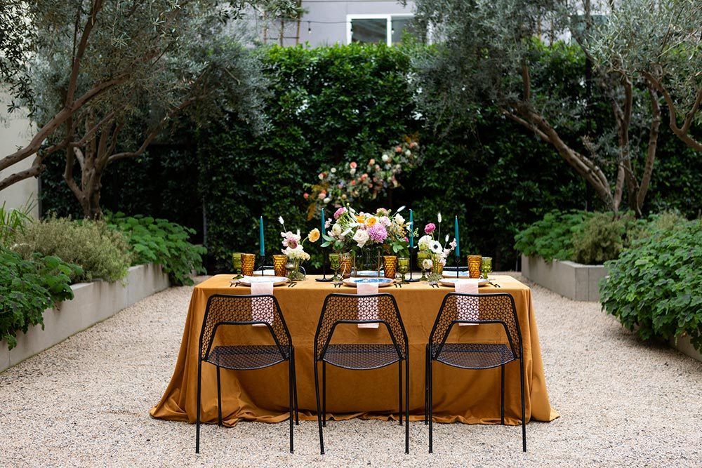 mustard tablescape with black wire chairs and marbled blue plates