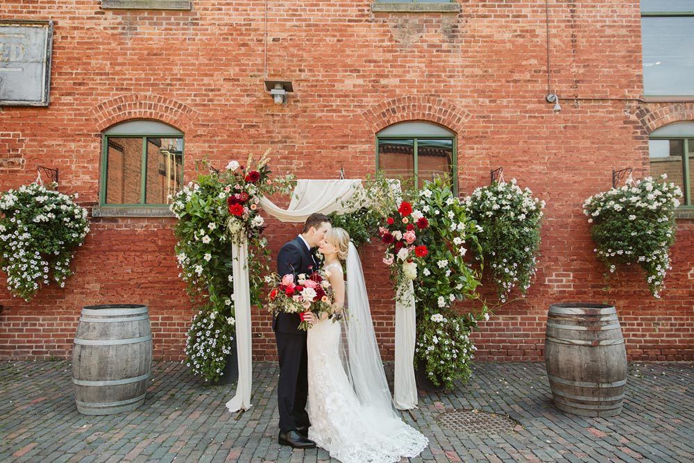 industrial chic wedding ceremony with burgundy flowers and romantic draping